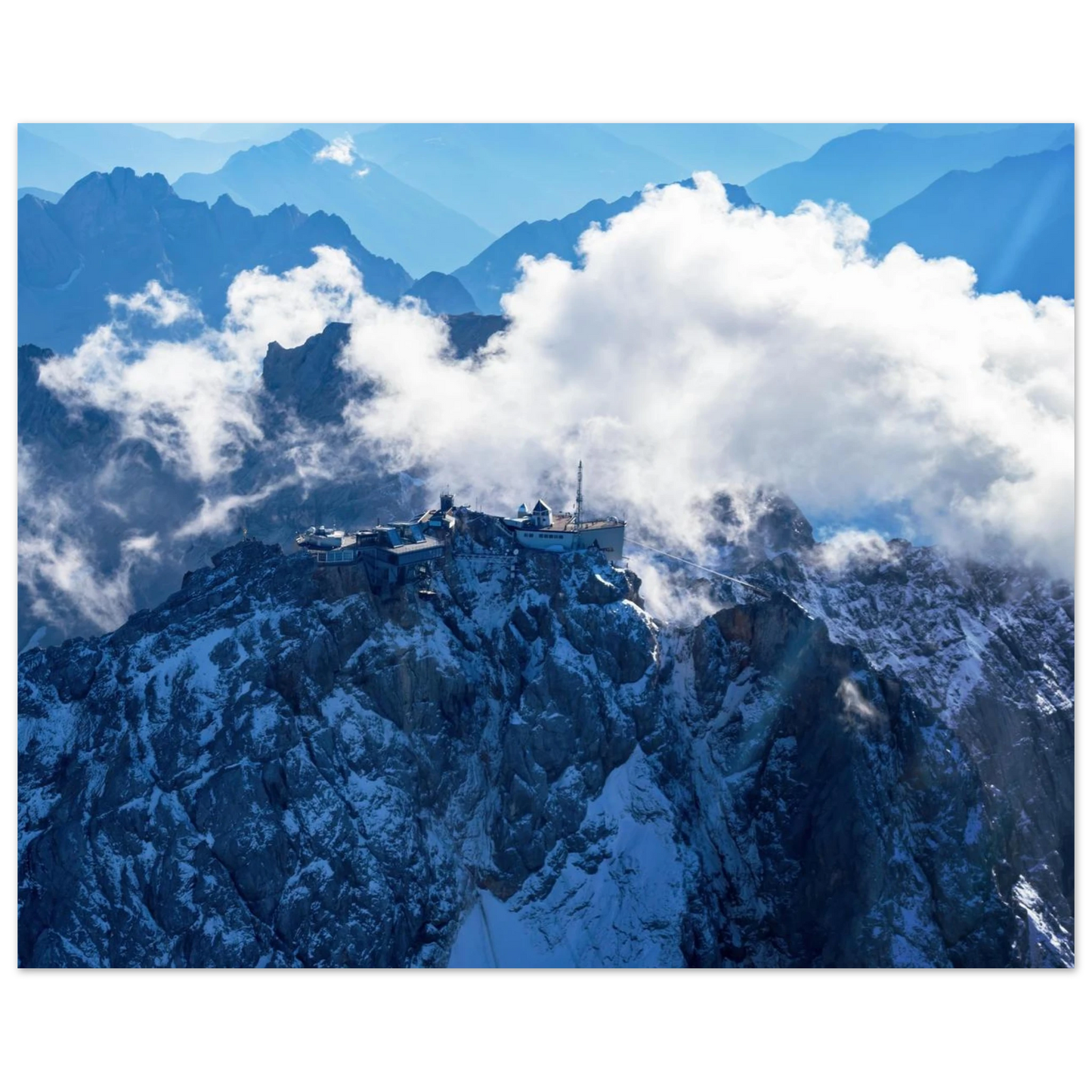 Wandbild alpine majesty gipfelstation im wolkenmeer mit blauen bergsilhouetten