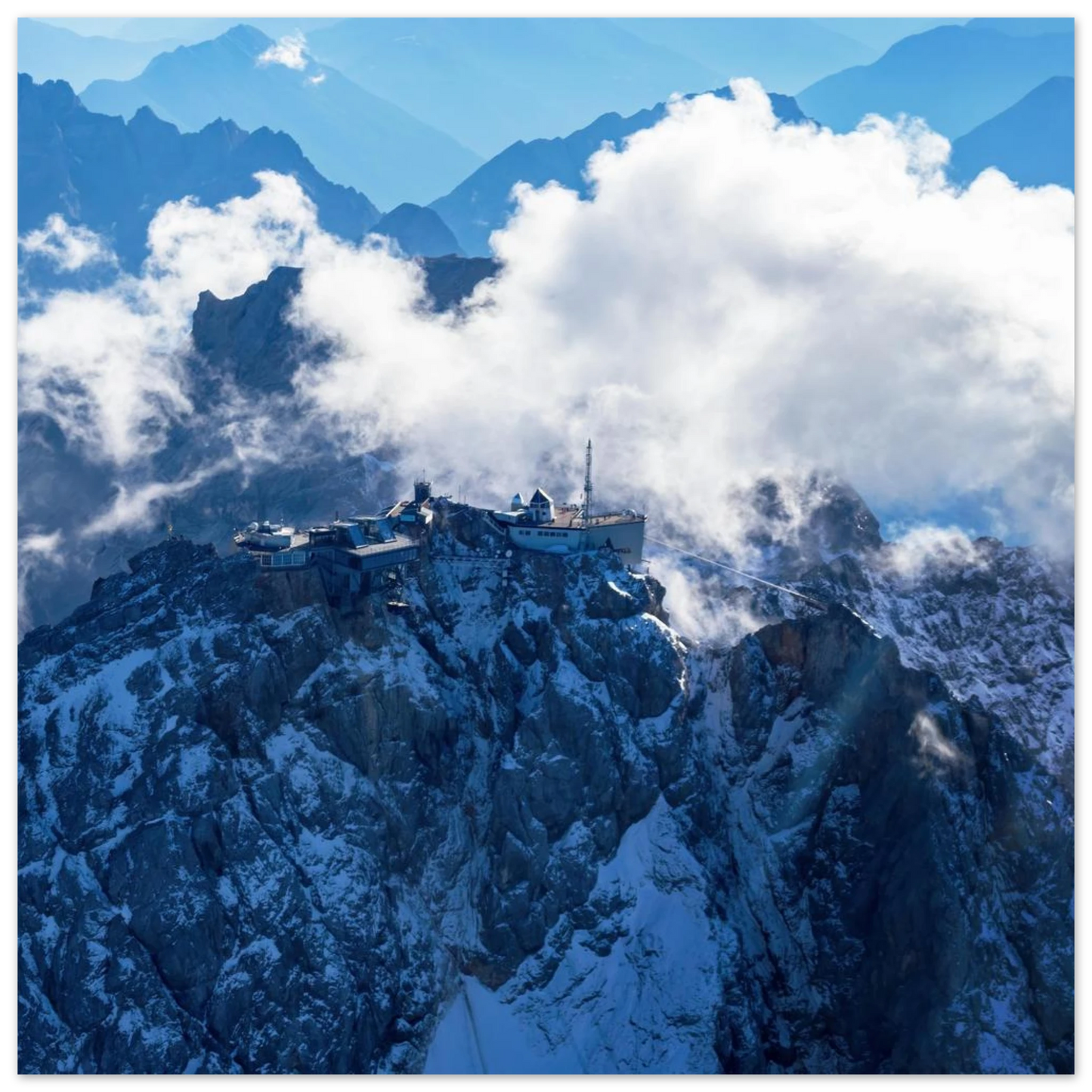 Wandbild alpine majesty gipfelstation im wolkenmeer mit blauen bergsilhouetten