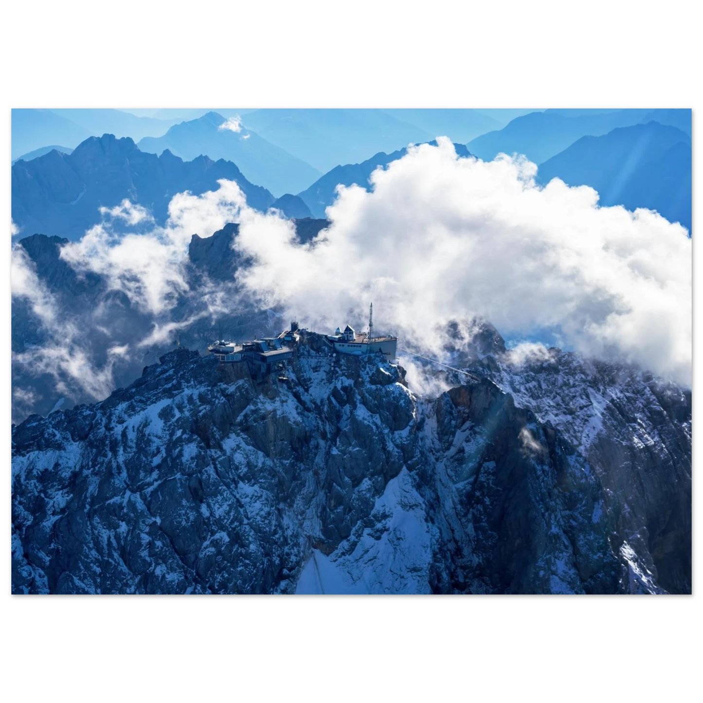 Wandbild alpine majesty gipfelstation im wolkenmeer mit blauen bergsilhouetten